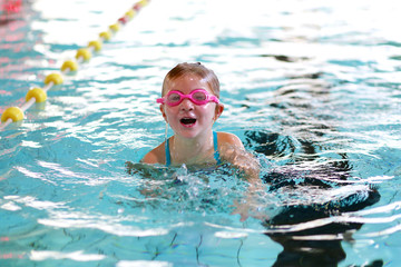 Little girl learning to swim in big sport pool. Swimming school for small children. Healthy kid...