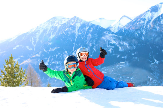 Happy children enjoying winter holidays in Alpine resort in Austria. Two brothers playing in the snow. Active sportive boys learning to ski. Beautiful Alps mountains in the background.