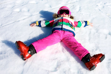 Fototapeta na wymiar Happy child enjoying winter vacation in Alpine resort in Austria. Little girl playing in the snow. Active sportive toddler learning to ski.