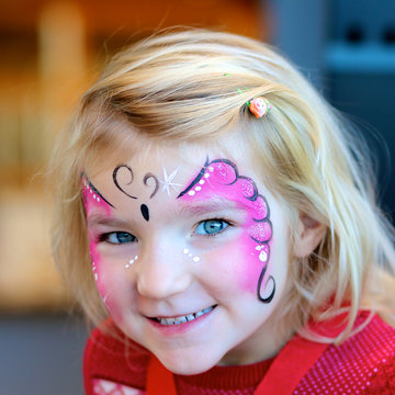 Cute little girl getting her face painted like a butterfly by face painting artist. Kids animation at the party.
