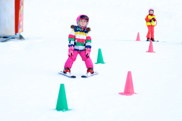 Happy child enjoying winter vacation in Alpine resort in Austria. Active sportive toddler girl...
