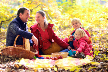 Family with kids having picnic in the forest. Mother, father and two children enjoying warm sunny...