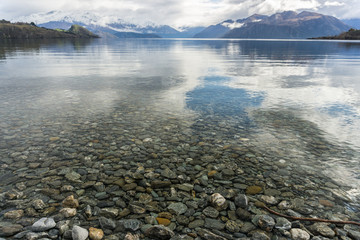 Stones through shallow water out to snow capped mountains - 133175014