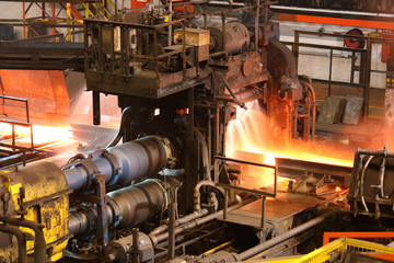 Hot steel being rolled to shape in mill in steel manufacturing plant. - obrazy, fototapety, plakaty
