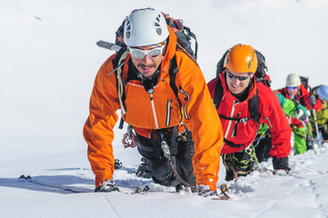 Bergführer klettert im Schnee mit seiner Gruppe am Seil