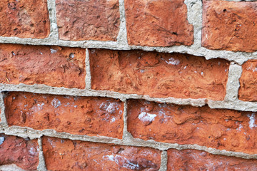Old brick wall with badly eroded bricks and prominent cement.