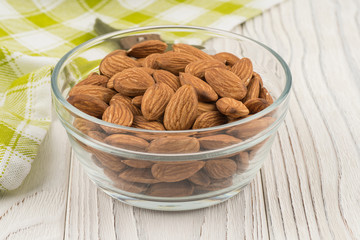 Almonds in a glass bowl on the old wooden table.