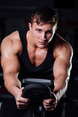 Fototapeta na wymiar Portrait of a handsome man workout on fitness the exercise bike dark at gym.