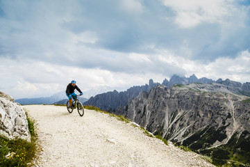 View of cyclist riding mountain bike on trail in Dolomites,Tre C