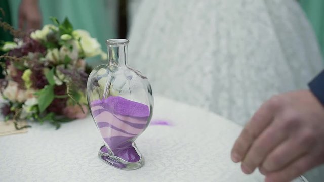 A wedding ceremony with a mixed family. The groom, mother, and son perform a unity sand ceremony mixing each of their colors into one beautiful piece of art.