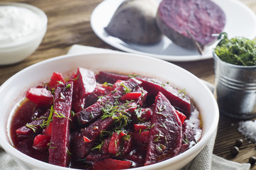 Vegetable soup - red borsch  in a white bowl on a rustic wooden background, clouse up. Healthy beetroot soup, vegetarian food. Delicious beet soup with sour cream.