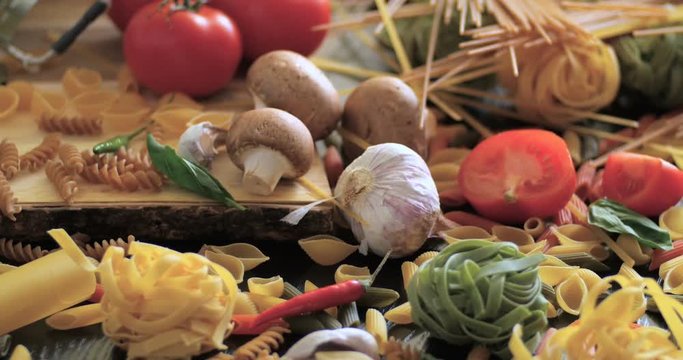 Dolly close up view of different variety of Italian pasta and ingredients