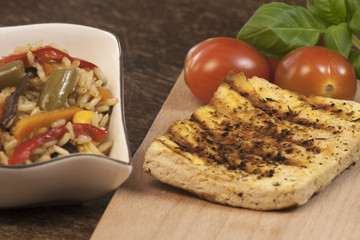 Vegan dinner. Grilled tofu with spices, rice with vegetables and fresh tomatoes