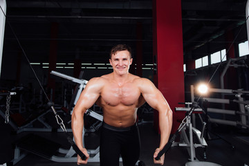 Obraz na płótnie Canvas big strong bodybuider without shirts demonstrate crossover exercises. The pectoral muscles and hard training