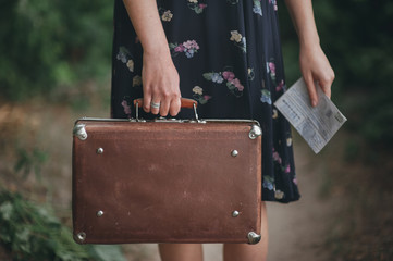girl in a vintage dress holding suitcase