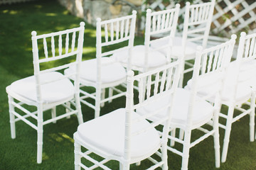 Beautiful white wedding chairs at the ceremony in the Park.