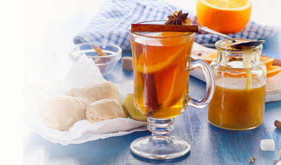 Ginger tea with orange and honey in glass cup.