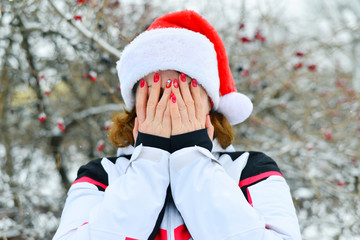 Woman in cap Santa Claus covers her face with her hands