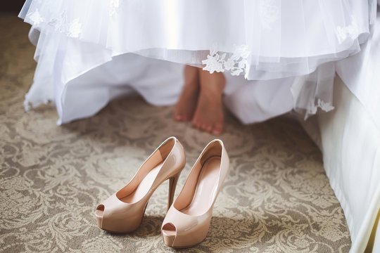 Bride's feet in shoes under wedding dress