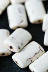 Collection of white rectangular magnesite beads on black cast iron plate.