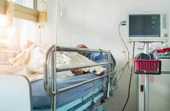 Close Up Bed Of  Hospital Ward Room During Elderly Patient Sleep With Digital Device For Measuring Blood Pressure Monitor