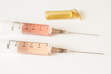 Syringes and open brown ampule on light background