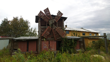 A small old abandoned mill near to a modern house