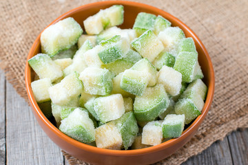 Frozen zucchini in a bowl on a wooden background