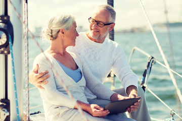 senior couple with tablet pc on sail boat or yacht