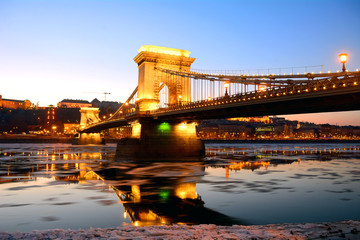Fototapeta premium The Chain Bridge at sunset over the icy Danube River, Budapest,