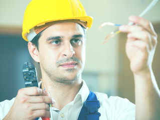Professionalhandyman in helmet working with wires