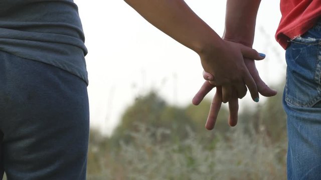 Young couple joining hands outdoor. Man and woman taking arms on nature background. Male and female hands comforting and stroking each other. Symbol of love and devotion. Romantic outside. Close up