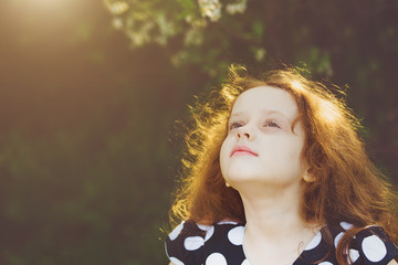 Little girl closed her eyes and breathes the fresh air in cherry