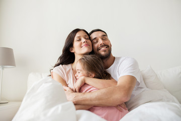 Fototapeta premium happy family hugging in bed at home