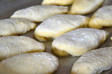 Fototapeta na wymiar Lots of pies on baking sheet of raw dough