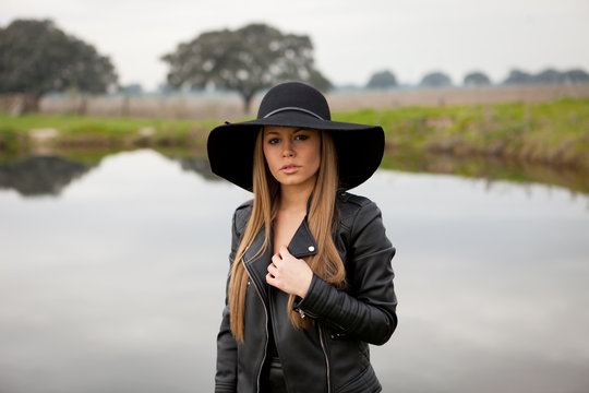 Stylish young woman with beautiful hat in the field