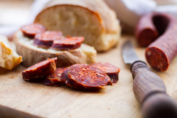 knife,  fresh bread and sausage on the table