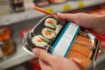 hands with sushi pack at grocery or supermarket