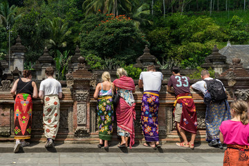 Temple Tourists. Tourists wearing traditional Balinese sarong at Tirta Empul temple, Ubud, Bali. - obrazy, fototapety, plakaty