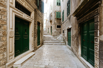 narrow European street with green doors in the historic center of Sibenik, Croatia.