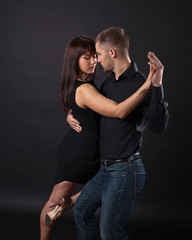 Young couple dancing on a dark background