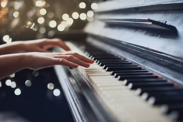 girl playing on an old piano. Beautiful blur background