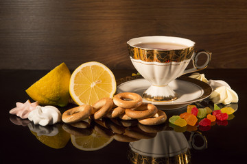 Cup of tea with a lemon and sweets. Still life against a dark background