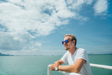 Portrait of a young successful man on the background of sky and sea landscape..Blonde with glasses...