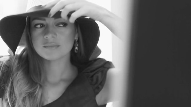 Woman in hat posing at big mirror closeup - slow motion 15 fps