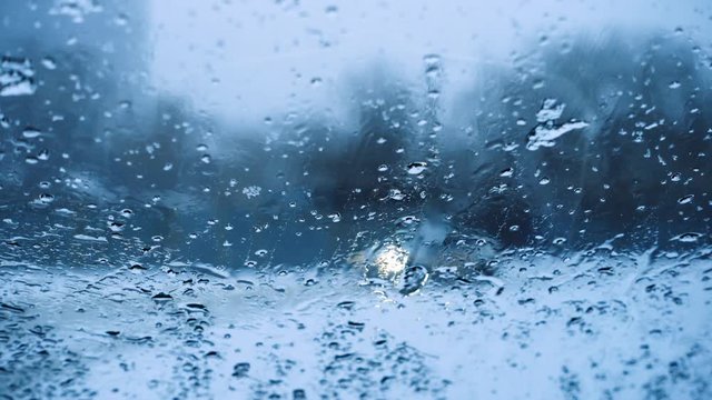 falling snow flakes and blurred cars on a road through the car window
