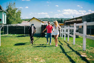 Young couple stay and walking near black horse at green farm © nataliakabliuk