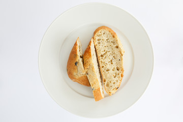 slices of bread on a white oval-shaped top view. European bread loaf of wheat flour with the addition of olive slices cut into pieces on a white plate