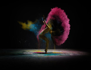 Dancer moving in cloud of coloured dust on scene