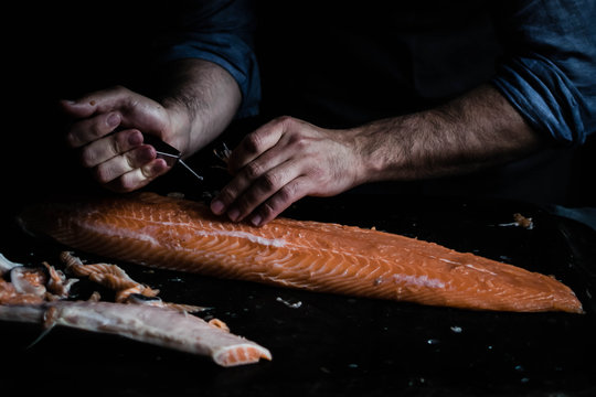 Close up of man's hand cutting salmon